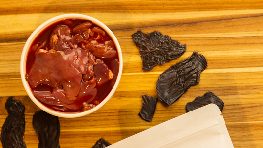 Bowl of chicken liver behind wooden board and