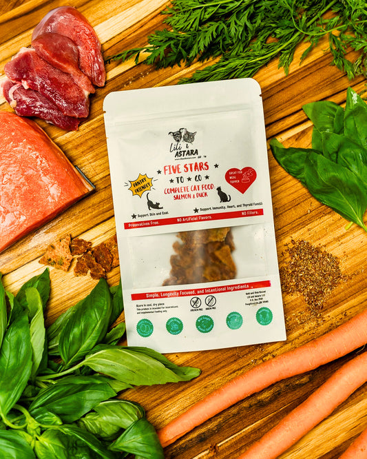 Package of 'Five Stars' cat food on a wooden cutting board with raw salmon, duck, carrots, and herbs.