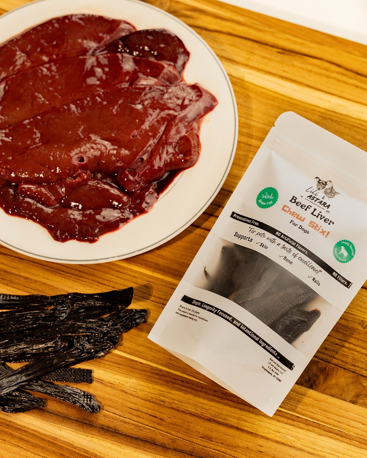 Dried beef liver on a plate with a package labeled 'Lili & Astara Beef Liver Chews' on a wooden surface.